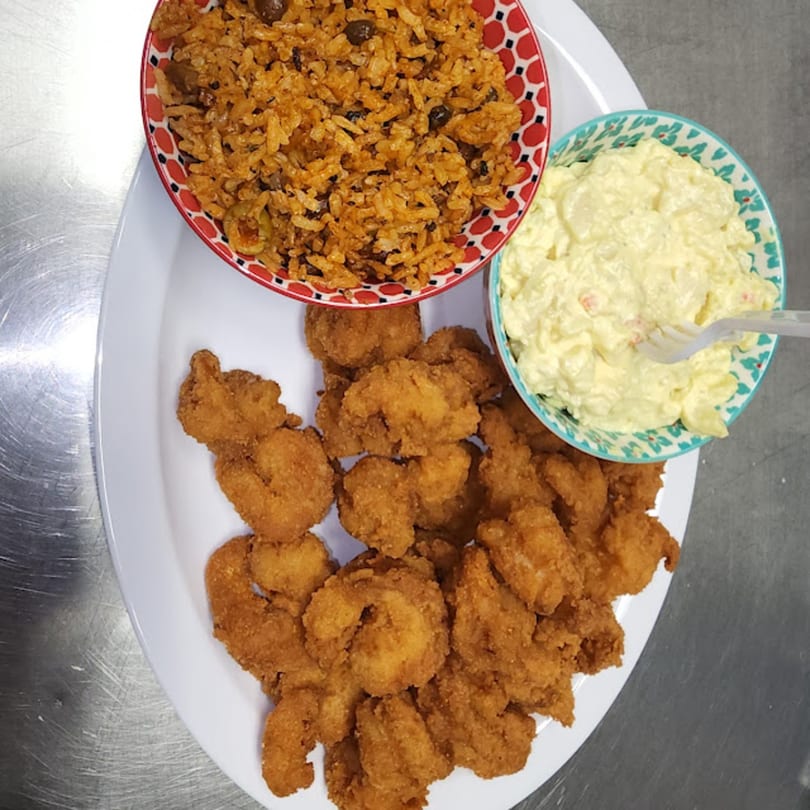 Latin Bliss fried shrimp, rice with beans, and potato salad on a white platter.